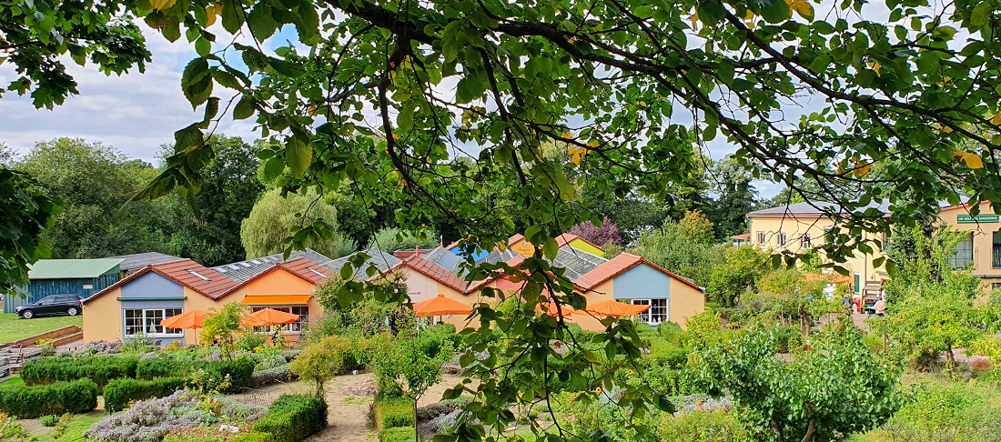 Die orangen Gebäude im Gewächshaus-Stil erinnern an eine ehemalige Gärtnerei auf dem Gelände. © GartenRadio.fm